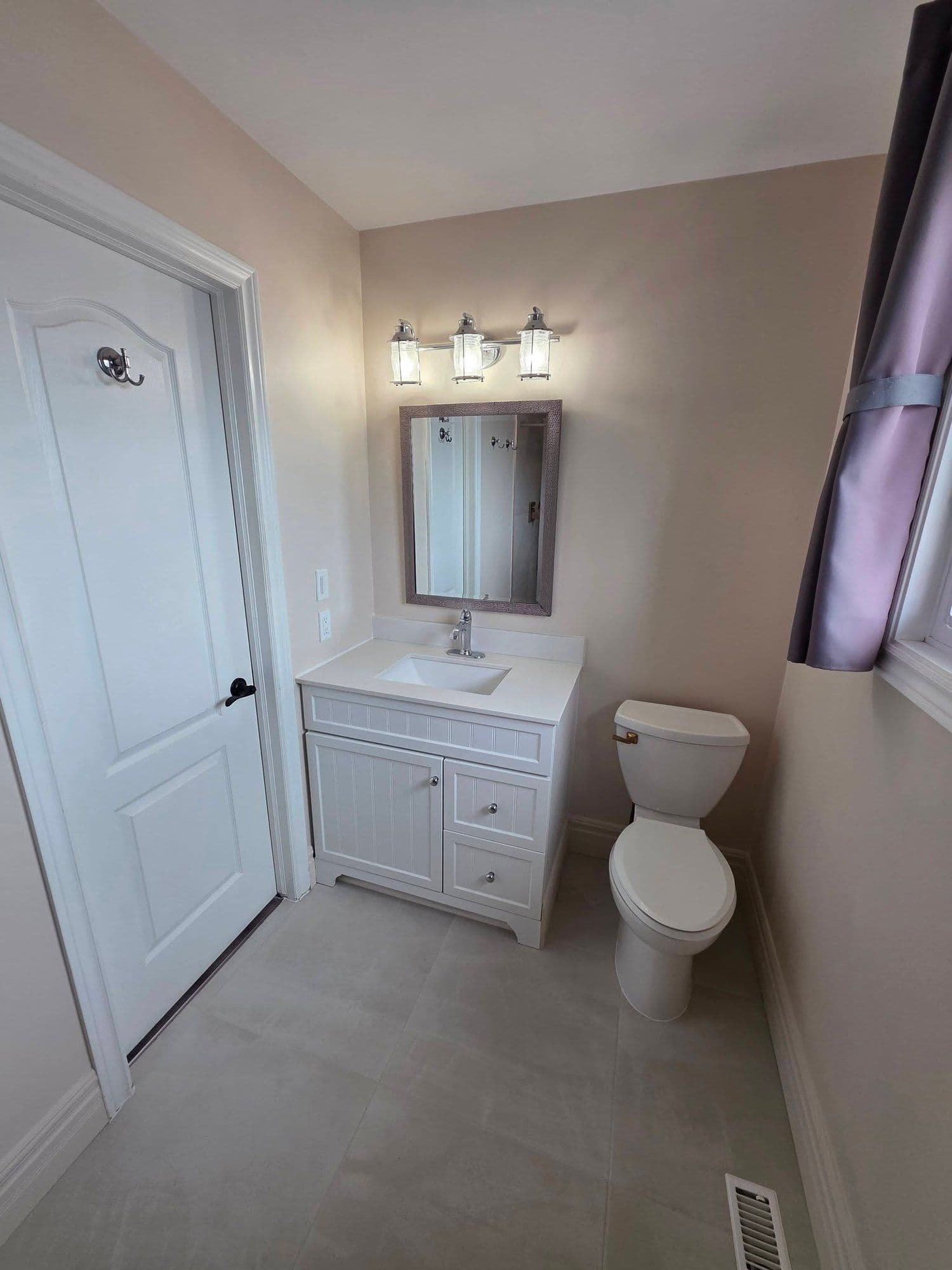 Renovated bathroom with a new white vanity and mirror