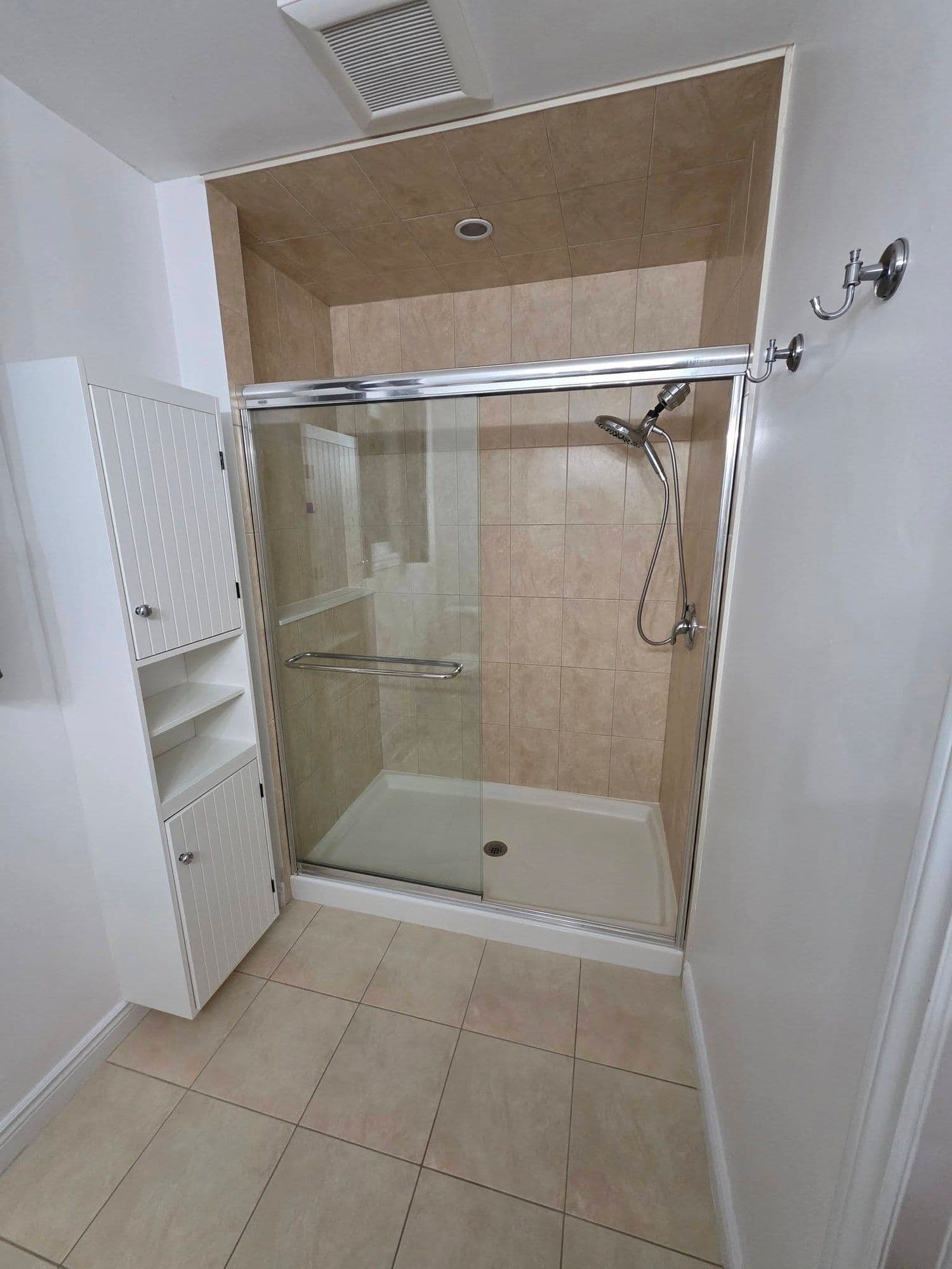 Tiled walk-in shower with a sliding glass door
