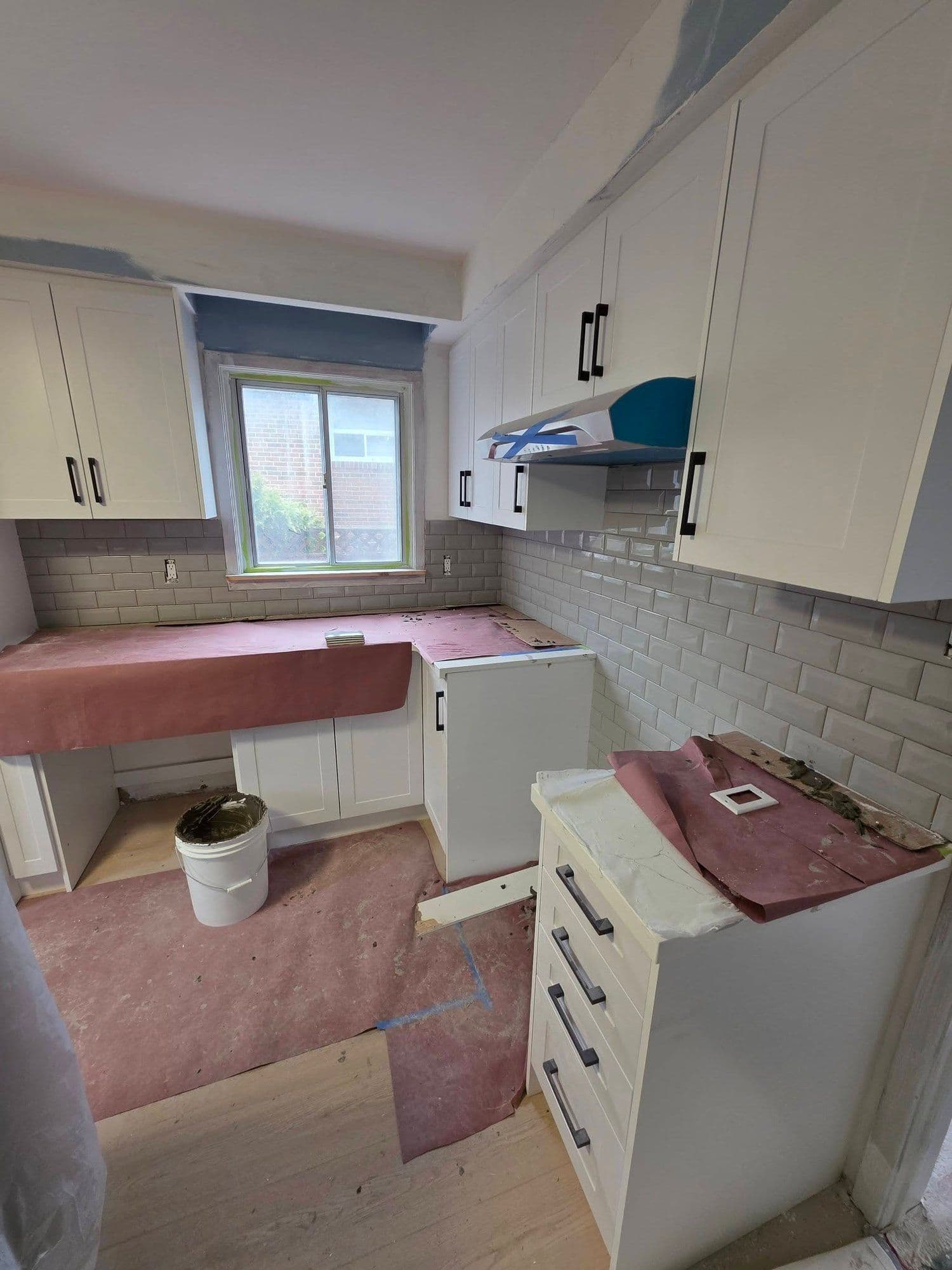 White shaker kitchen cabinets and subway tile backsplash being installed